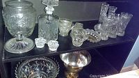 Full view of various glassware items including decanter, glass jar, candlestick holders, small creamers, covered butter dish, and a candy bowl.