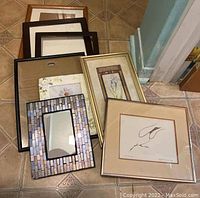 Collection of assorted picture frames and Benjamin Chee Chee print shown on tiled floor. Frames vary in sizes approximately 8x10 to 10x14 inches and styles.