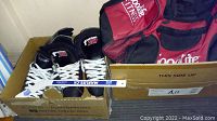 Pair of black boys CCM Fusion 32 hockey skates in a box alongside a red and black Goodlife Fitness bag