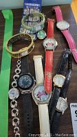 Nine assorted ladies watches arranged on table showing various strap colors including two with Disney Minnie Mouse faces
