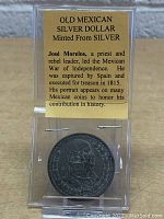 Photo showing coin in display case with informational card describing José Morelos and historical context.
