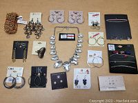 Photo showing a variety of new name brand jewelry pieces spread out on a table including earrings, a large statement necklace, bracelets, anklets, toe rings, and charms.