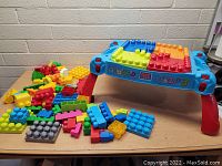 Mega Bloks fold-up play table with red legs and a large assortment of colorful building blocks on top and next to the table.