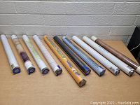 Lot of 10 rolled artwork poster prints shown from front view on table