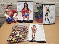 Lot of three women's costumes displayed on a table, including packaged Hippie, Wonder Woman, and Sexy Firewoman costumes.