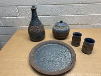 Set of five vintage stoneware items on table with brick wall background.