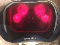 Front view showing four red glowing massage nodes under mesh fabric, indicating heat and rotation function active. Homedics brand logo beneath the nodes.