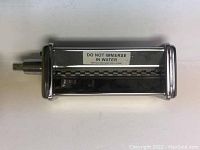 Stainless steel pasta roller attachment with warning label and Kitchenaid embossing.