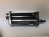 Close-up photo of the KitchenAid roller attachment showing two rollers and adjustment knob.