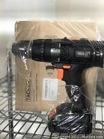 Tacklife cordless drill in packaging on metal shelf showing drill and box