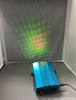 Blue metal laser stage light powered and projecting green and red laser lights.