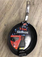 Top view of the T-FAL Sapphire branded sauté pan showing label details with heat mastery features and 12 inch size indication.