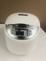 Front view of Tiger JAX-R18U rice cooker with closed lid, digital display, and control buttons visible