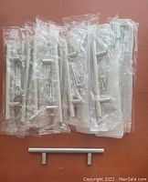 Set of 12 silver modern cabinet handles individually wrapped, showing the quantity and packaging.