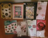 Full view of the lot items including candy molds, a picture frame, stained glass coloring book, chocolate molds, decorating bags, and snowman cookie cutter pieces.