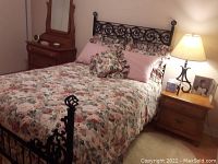 Bed made with floral duvet cover, two pillow shams, bed skirt with visible floral print in green, burgundy, cream tones, taken from side angle.