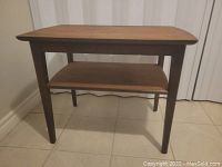 Front view of the mid century modern wooden side table showing tapered legs and lower shelf