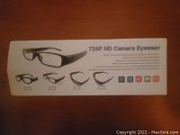 Photo of packaging showing product name and images of four different styles of camera eyewear with 720P HD video capability and icons representing features.