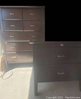 Photo showing the full dresser next to the night table, both dark wood with metal handles, some light glare visible
