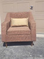 Front view of the mid-century upholstered armchair with a light floral pattern, rectangular throw cushion on seat (not included). Chair legs made of wood.