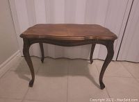 Front view of solid walnut table showing carved legs and shaped apron