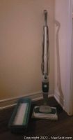Swiffer BISSELL STEAMBOOST Steam Mop upright, showing mop with attached steam pad and power button, placed near wall.
