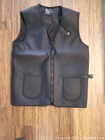 Front view of black Genovega heated vest, showing the vest details including zipper, pockets, and control button
