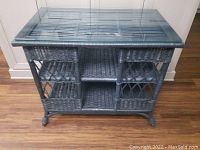 Front top-down view of vintage dark blue wicker console table showing glass top and shelves inside.