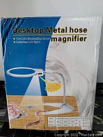 Box showing product name Desktop Metal Hose Magnifier with LED lights and image of the magnifier placed on a table with a flexible metal tube, ring LED light, and lens. Model and lens size details included on box.