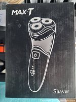 Front of the box showing the MAX-T shaver model with power button and LCD display illustration