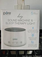Package front showing the product name, image, and key features including 5 year warranty, 6 sleep sounds, breathing light, and auto sleep timer.