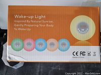 Photo of the box showing wake-up light alarm clock with 6 color options and features such as natural sunrise simulation to wake up.
