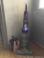 Photo of the upright Dyson vacuum cleaner with dust container and purple cyclone.