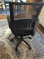 Back view of the black office chair showing the mesh backrest and five-star wheeled base.