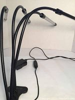 Photo showing the three flexible black gooseneck arms with LED tubes and the base clamp.