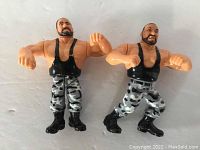 Front view of two WWF Hasbro Bushwacker action figures, showing details of face, attire, and pose.