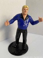 Photo of the Bobby Heenan WWF action figure by LJN showing the figure in blue and black clothing with thumbs up on a base.