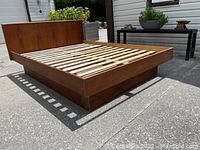 Overall view of the full-size bed frame angled front-left showing headboard, platform and base