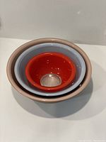 Three Pyrex mixing bowls nested inside each other showing red, blue, and tan colors.