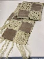 Scarf laid flat showing alternating suede and crochet patchwork and fringe ends