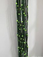 Close-up of the painted green bamboo segments with lime green plastic beads showing texture and color.