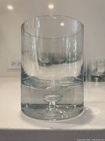 Close-up of a single crystal whiskey glass showing its heavy thick base with a clear blown bubble inside.