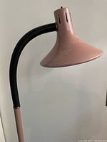 Close-up photo of pink metal lampshade with black rubberized goose neck.