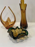 Trio showing the three glass pieces with amber swoop vase, U-shaped vase with bubble detail and green/amber ruffled edge bowl