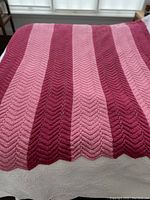 Full view of blanket spread out showing raspberry and pink chevron stripe pattern.