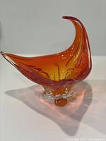 Orange red mid-century modern glass bowl shown from side angle highlighting sculptural form.