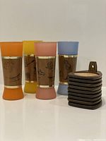Photo showing all four colored frosted glasses with wood veneer and gold trim alongside stackable wooden coasters set.
