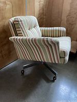 Side view of the Mid-Century Modern striped swivel chair showing fabric upholstery and metal base with Shepherd castor wheels.