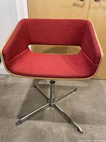 Front angle of vintage mid-century modern swivel chair showing ruby red fabric seat and wood wrap on sides with metal base.