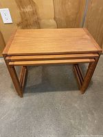 Set of three rectangular teak nesting tables stacked together, showcasing size gradation and nesting function.